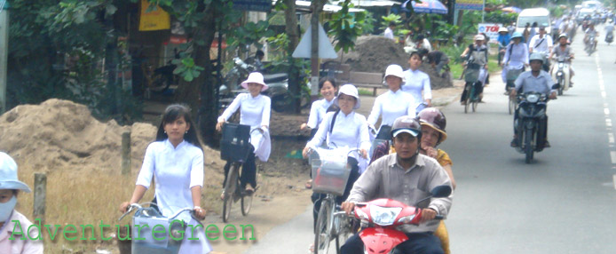 Cycling girls in Ao Dai at My Tho, Mekong Delta, Vietnam
